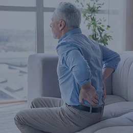 older man with chronic back pain holding his back